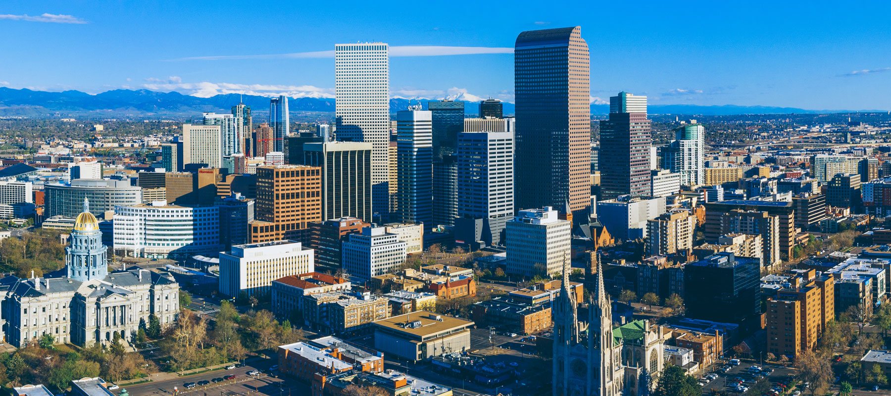Downtown Denver skyline with the Colorado State Capitol and the Rocky Mountains behind it